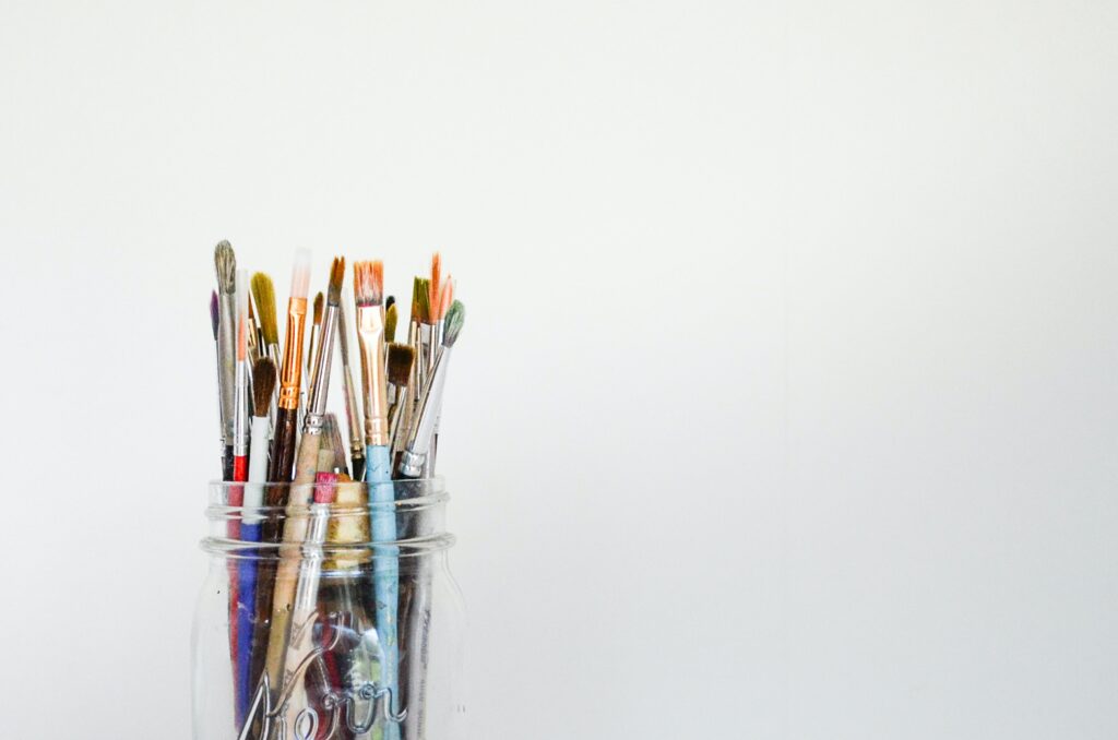 paintbrushes in a jar against a white background